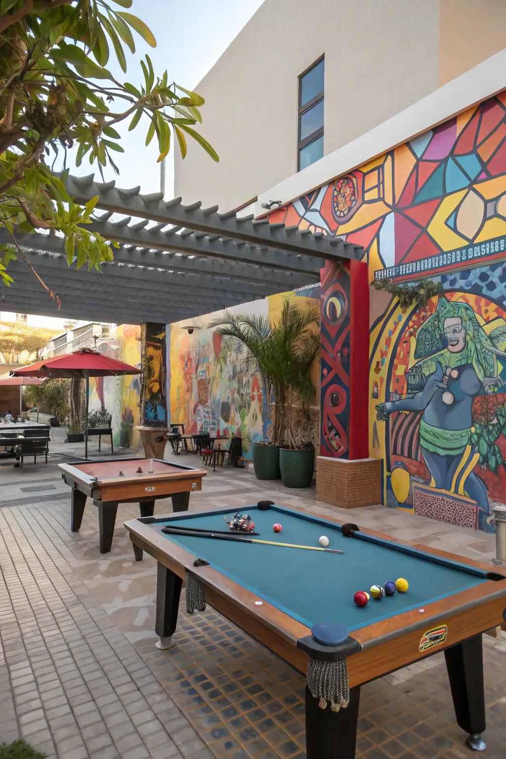 An artistic outdoor pool table area with murals and sculptures.