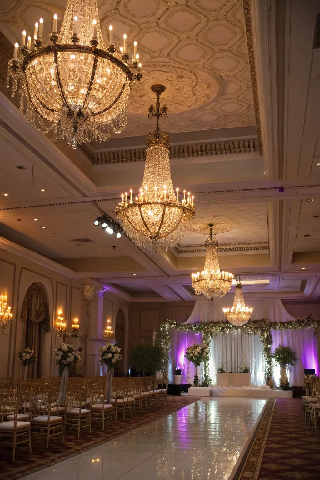 A wedding venue featuring sophisticated lighting concepts with chandeliers and uplighting.