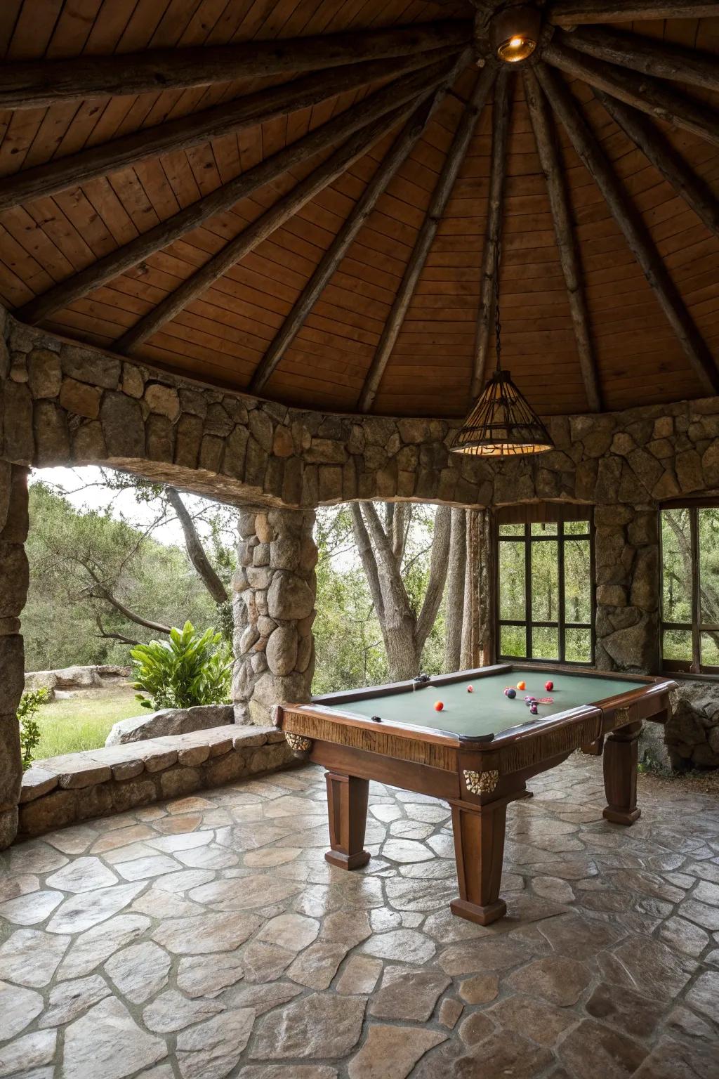 A rustic stone pavilion housing a pool table in a natural setting.